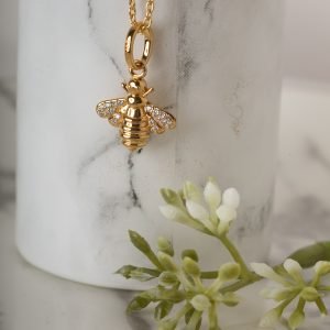 golden-sparkly-bee-necklace-hanging-from-a-china-jug-with-white-flowers