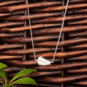 Feather-necklace-in-silver-and-gold-hanging-from-wicker-basket