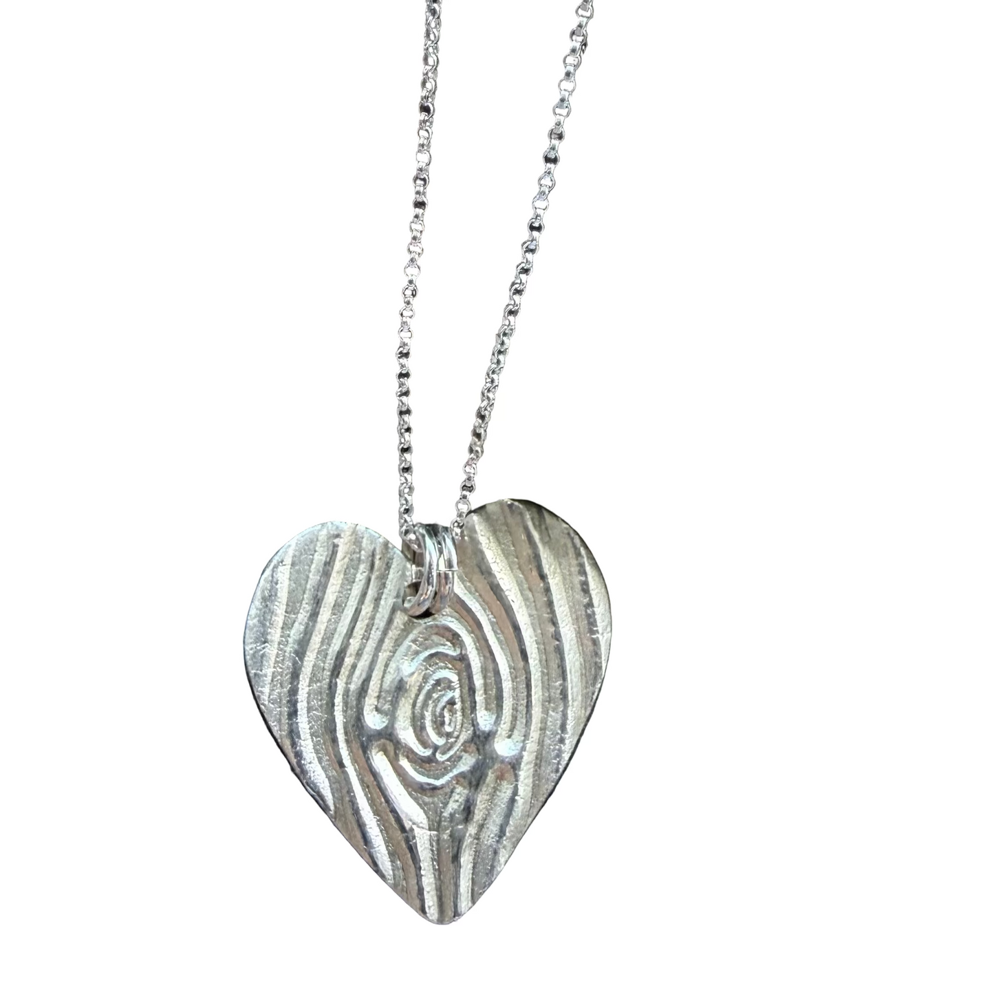 Silver heart-shaped pendant on a chain resting on a stone surface