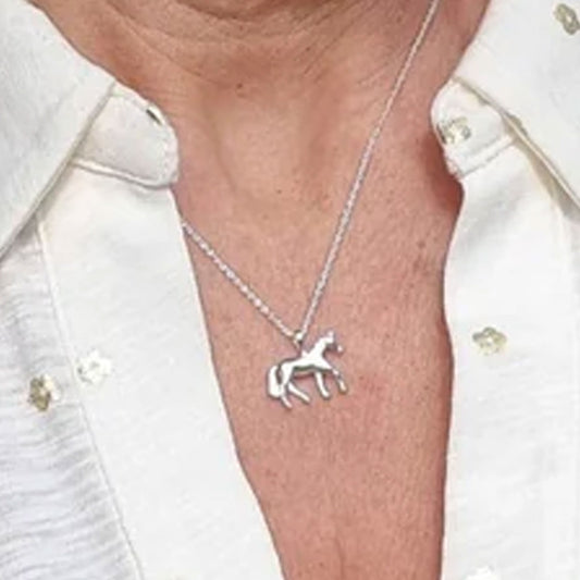 Silver horse pendant necklace on a person wearing a white shirt.