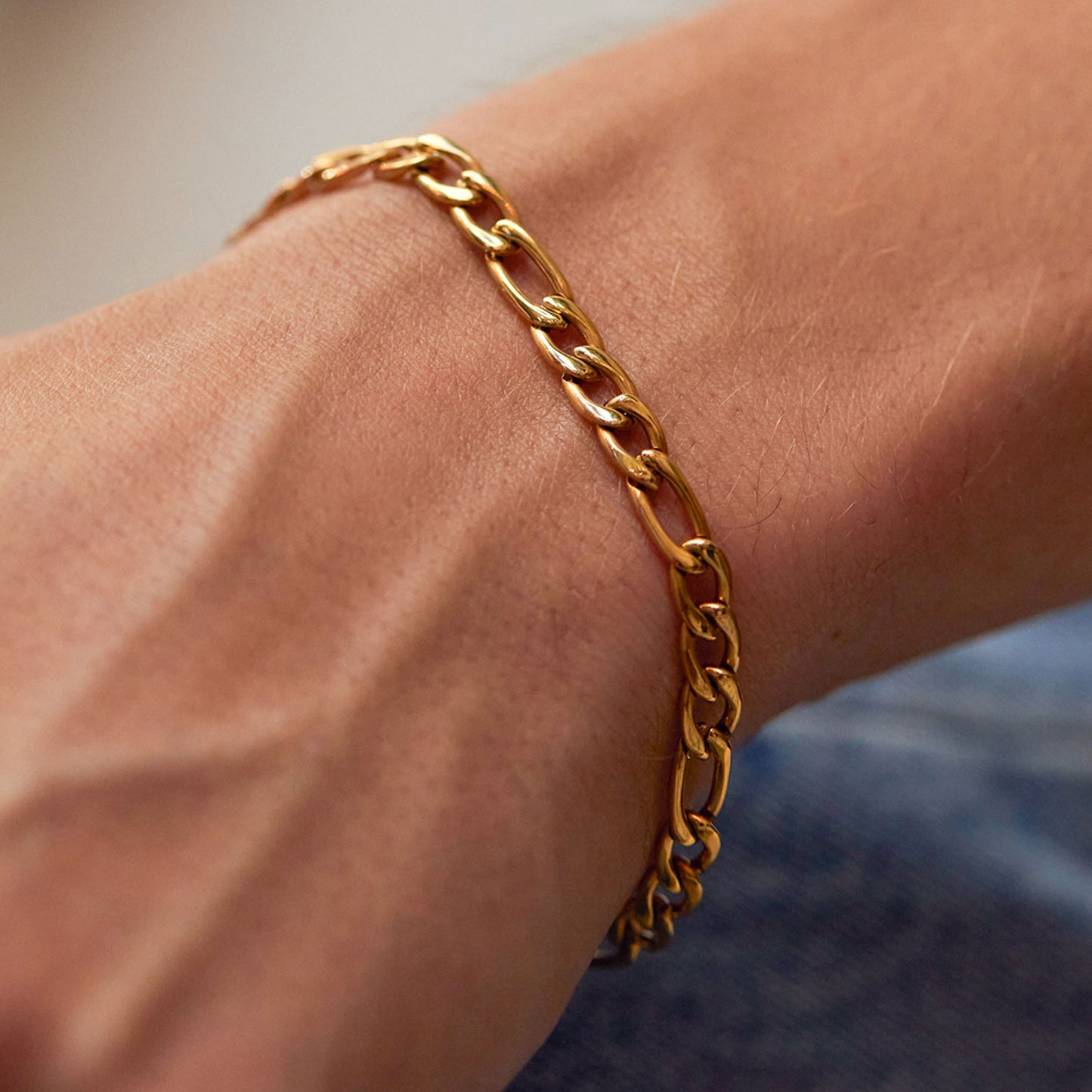 Gold chain bracelet on a wrist with a blurred background