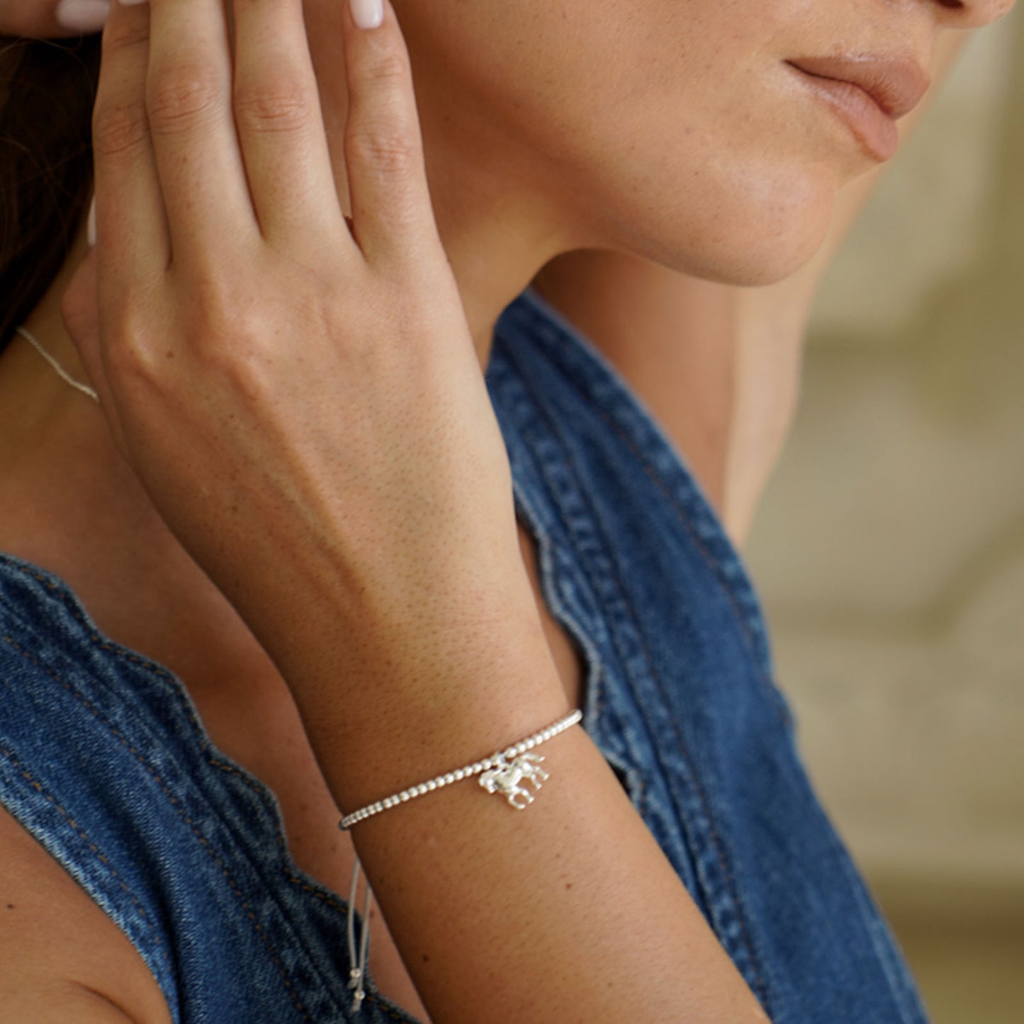Close-up of a person wearing a delicate horse bracelet on a blurred background
