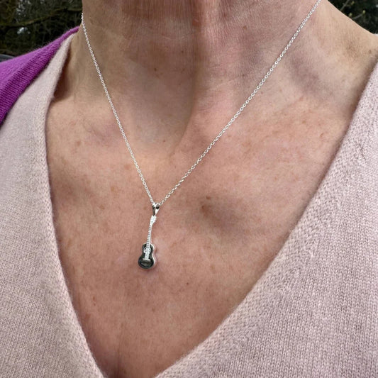 Close-up of a necklace with a pendant on a person wearing a light pink sweater.