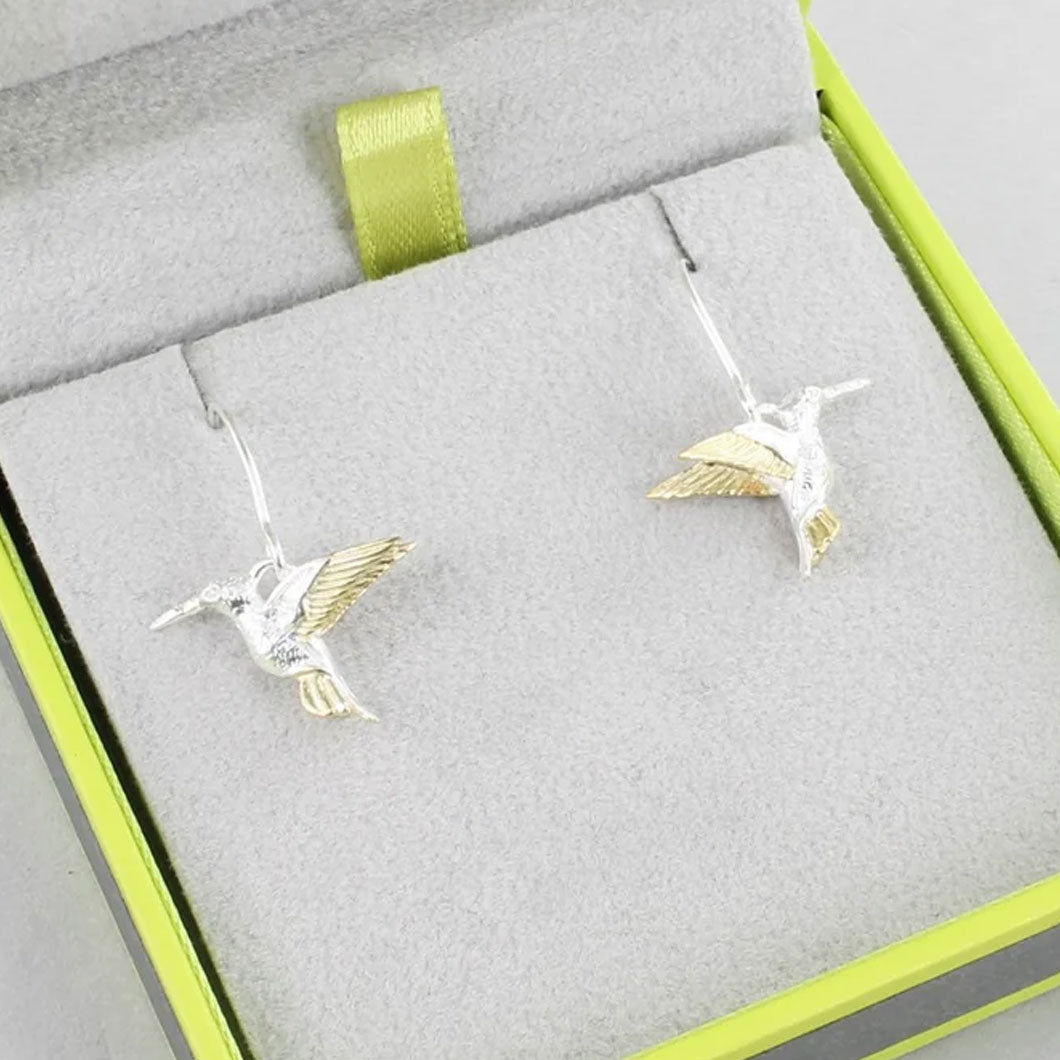 Silver and gold hummingbird earrings in a jewelry box with a green ribbon.