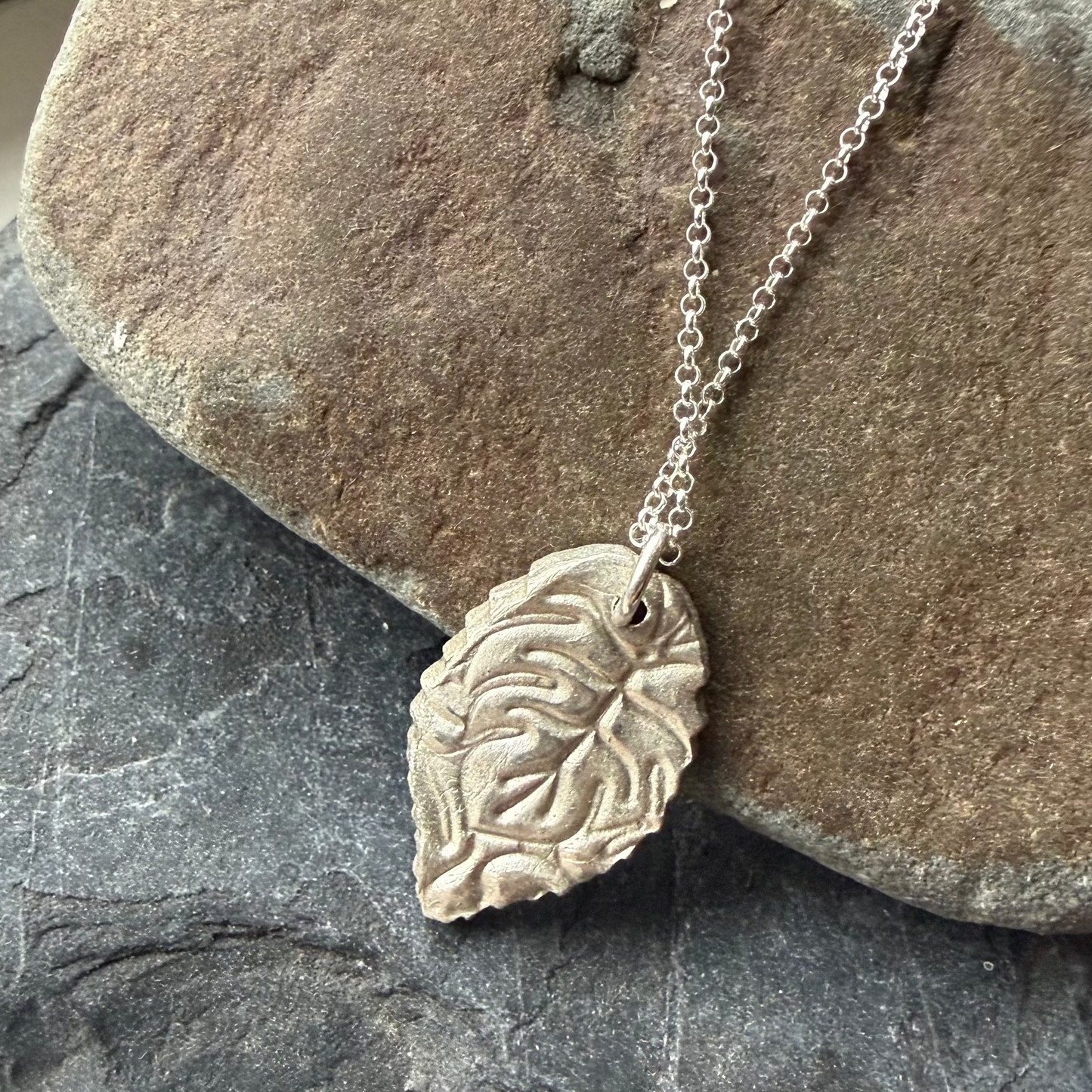 Reverse of Silver leaf necklace on a rock