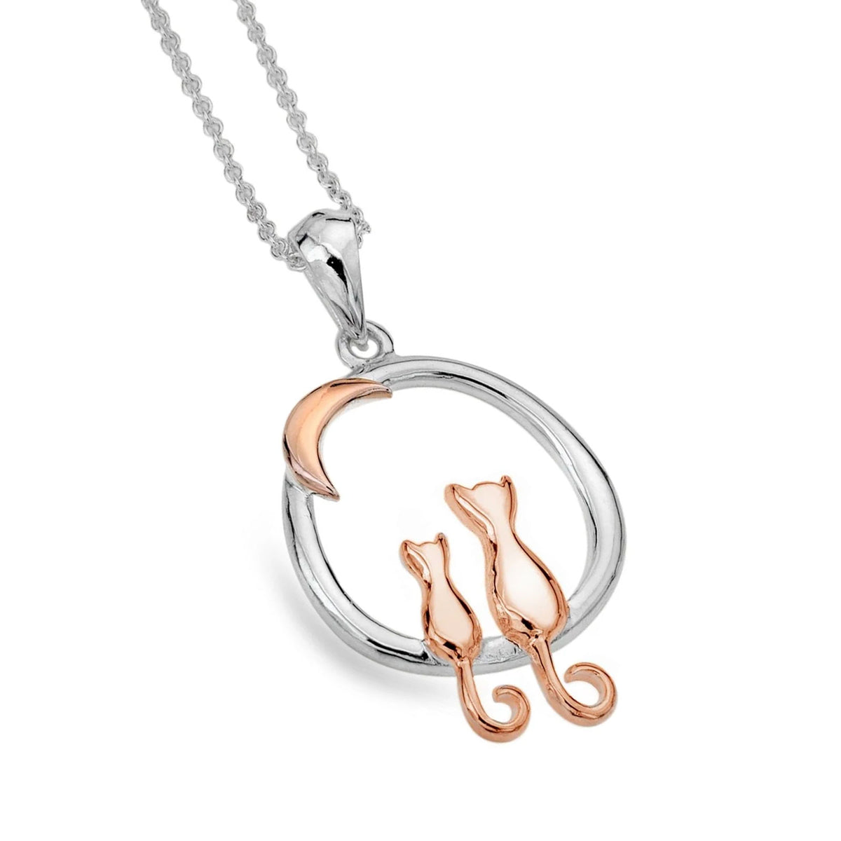 A silver and rose gold pendant necklace featuring two small cat silhouettes sitting inside a circular frame with a crescent moon, shown on a white background.