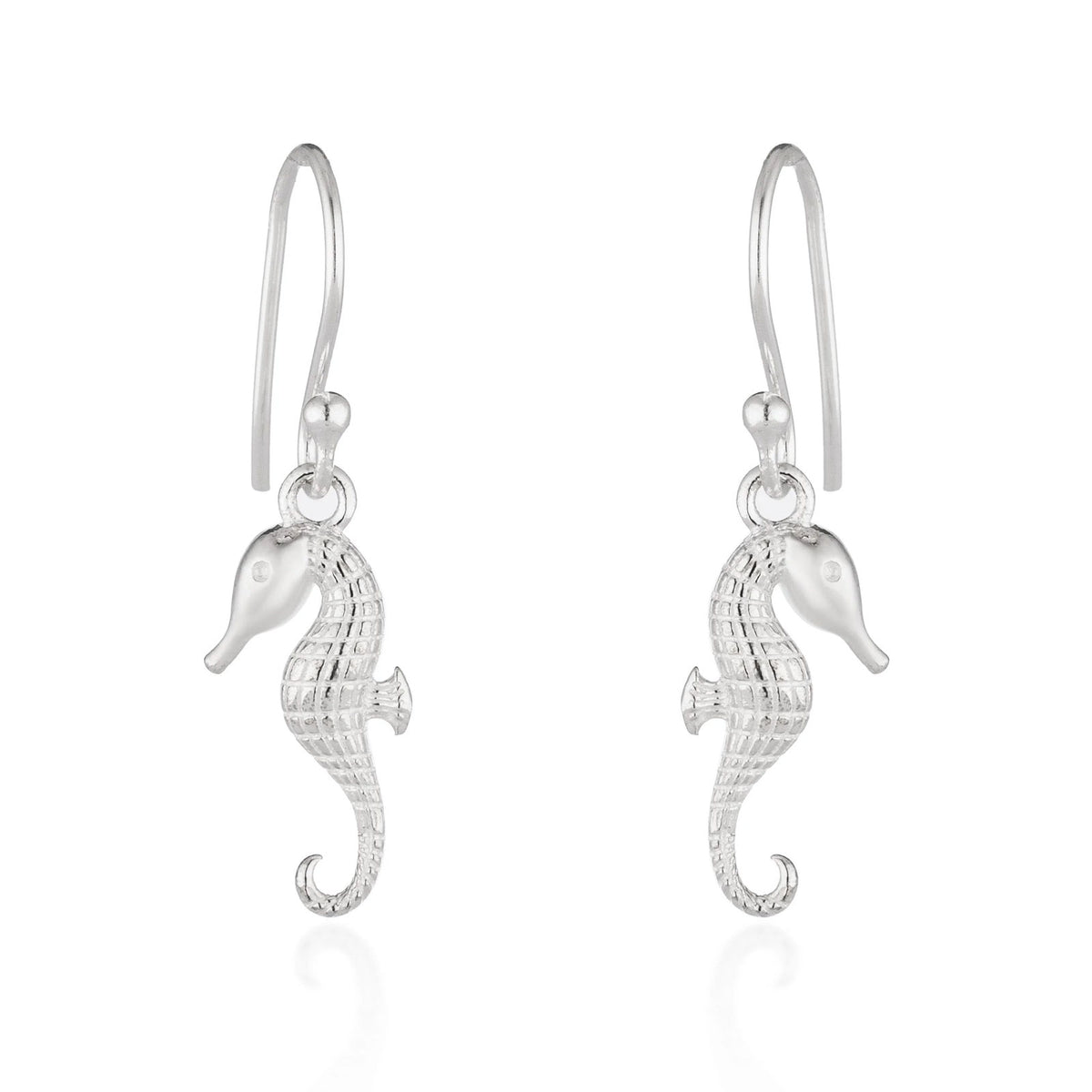 A pair of silver seahorse drop earrings with textured bodies and curved hook backs, shown on a clean white background with a soft reflection below.
