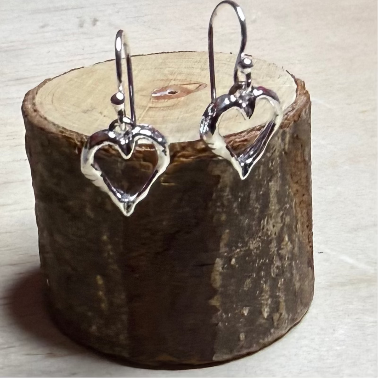 silver earrings on wooden log