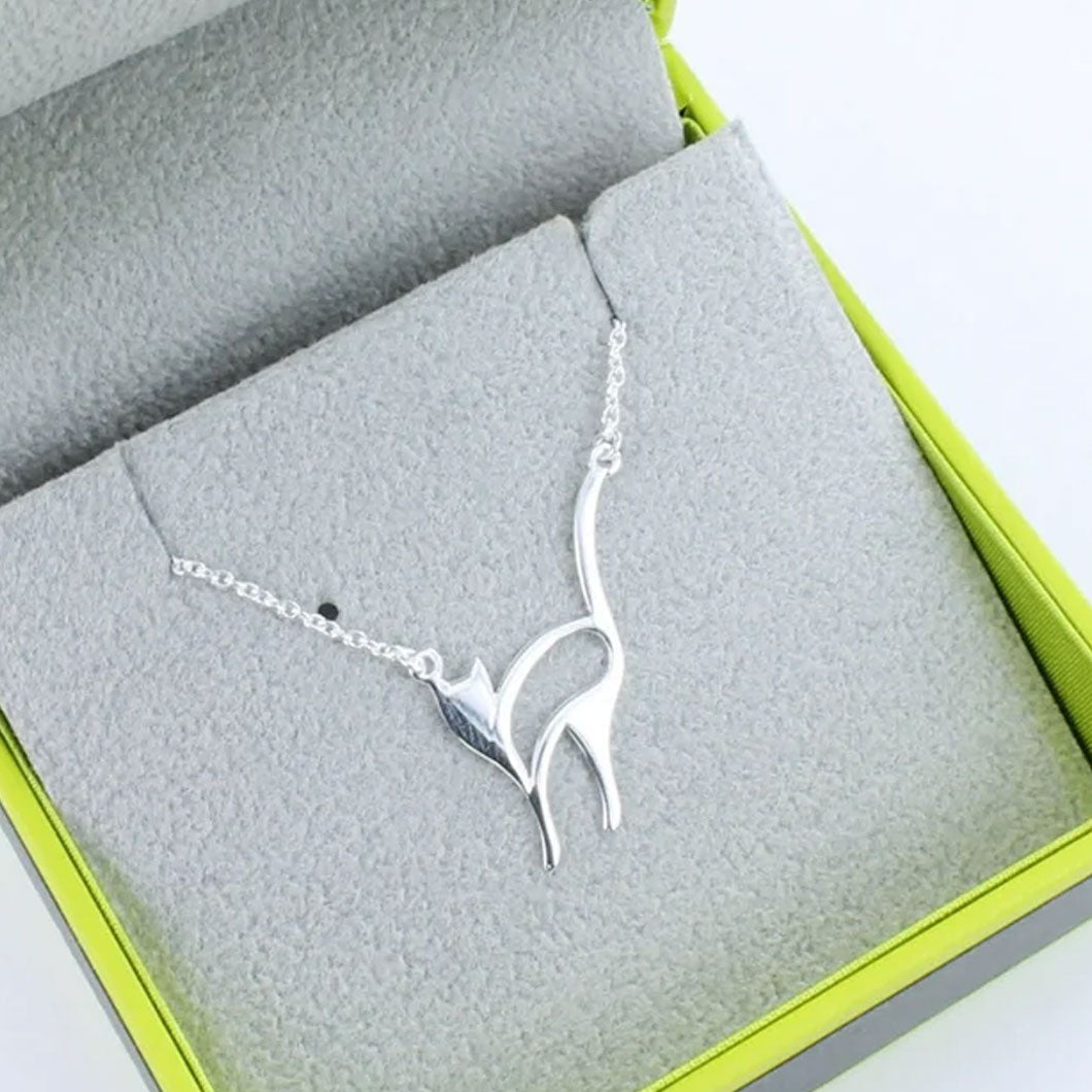 Silver bird-shaped necklace on a gray fabric surface