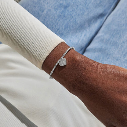 Silver heart bracelet on a wrist with a blurred background