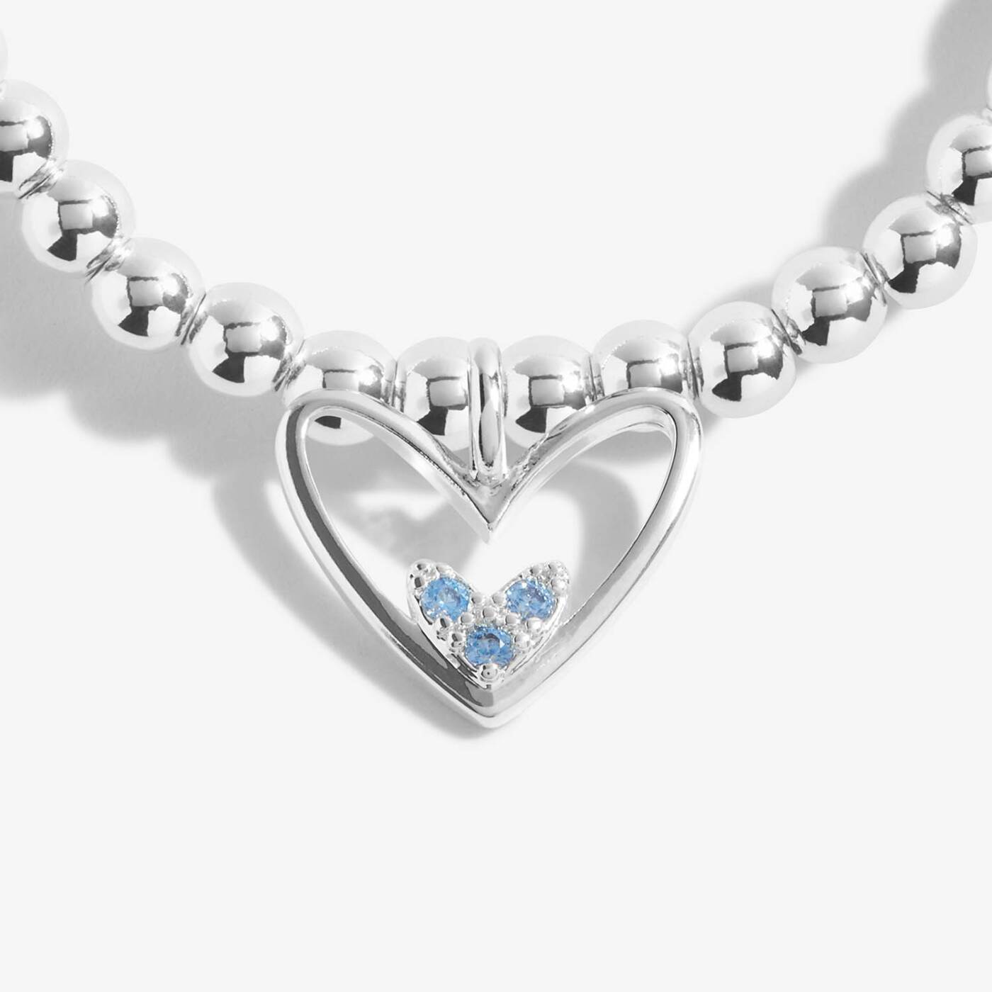 Silver heart-shaped pendant with blue gemstones on a white background