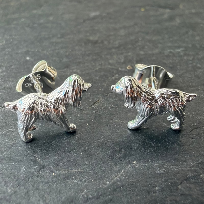 Silver spaniel dog-shaped earrings on a dark surface
