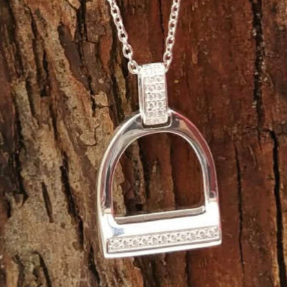 Silver stirrup pendant necklace on a wooden background