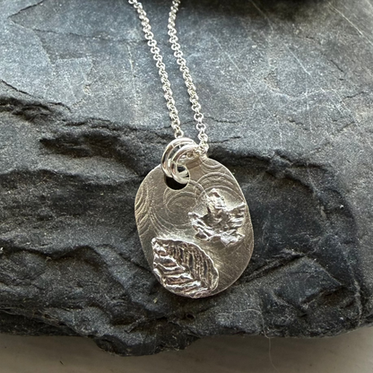 Silver necklace with a pendant on a dark stone surface