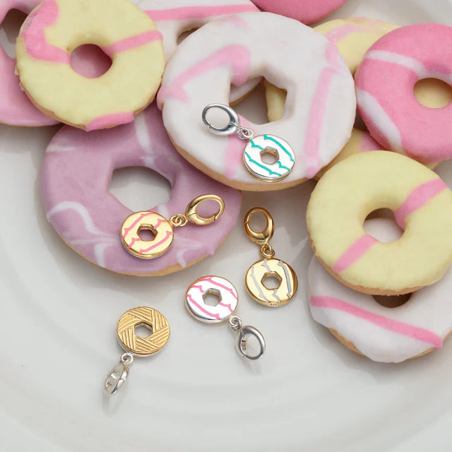 Donut-shaped cookies with colorful glaze and donut-themed Charms on a white background