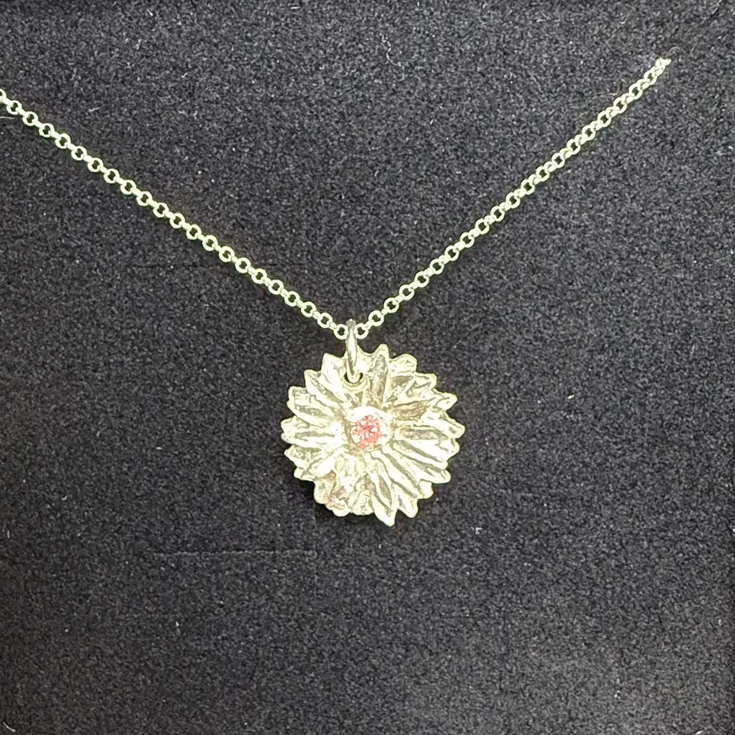 Necklace with a floral pendant in a black jewelry box on a wooden surface