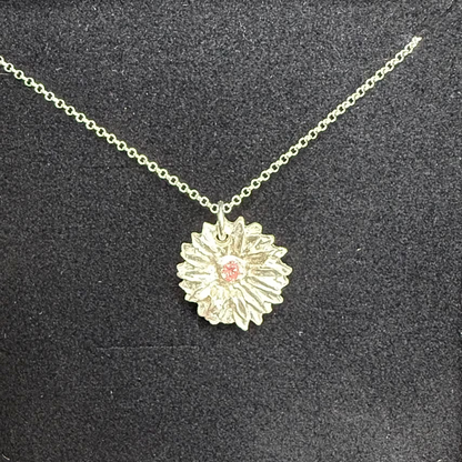 Necklace with a floral pendant in a black jewelry box on a wooden surface