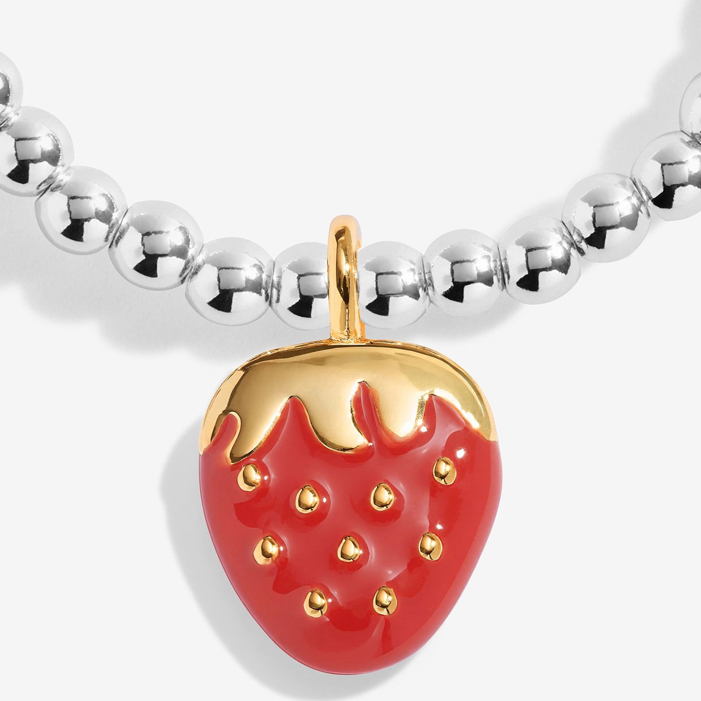 A close-up of a beaded necklace featuring a strawberry-shaped pendant. The necklace has shiny silver metallic beads, and the central pendant is red with a gold top and small gold details.