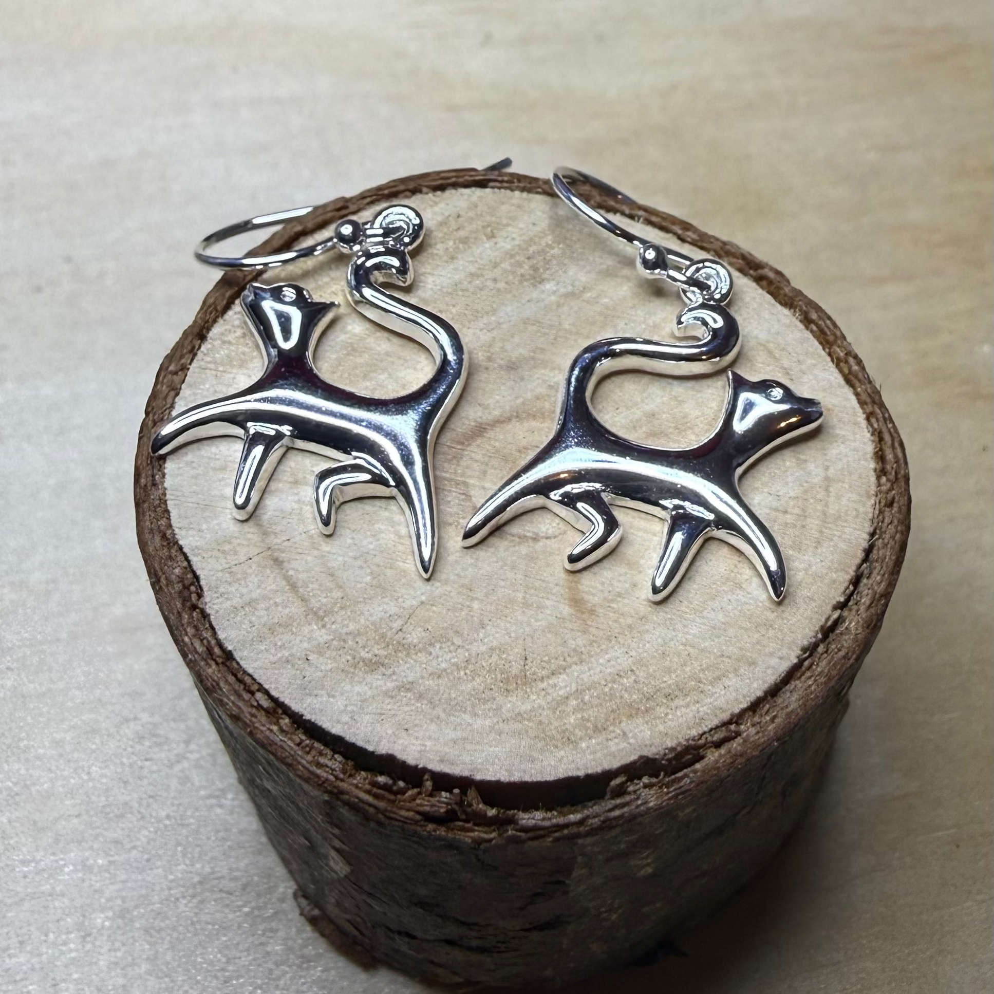 Silver cat earrings on a wooden block