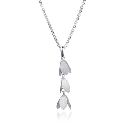 A silver pendant necklace featuring three vertically stacked, textured petal-like charms on a delicate chain, set against a plain white background with a soft reflection below.