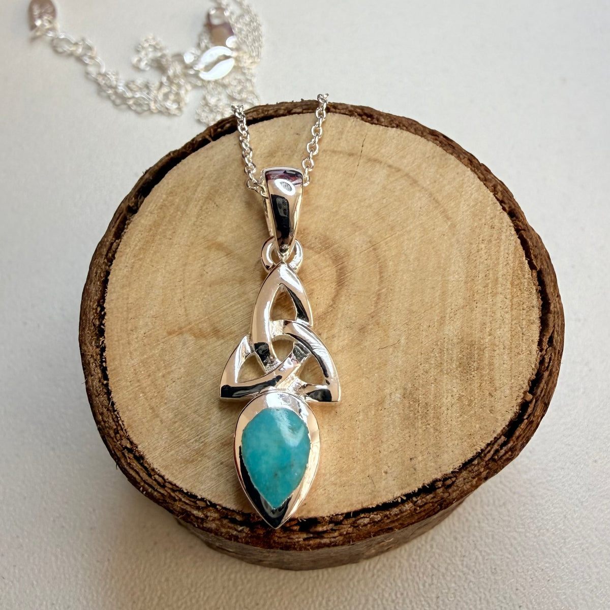 celtic knot silver and turquoise necklace on wooden log