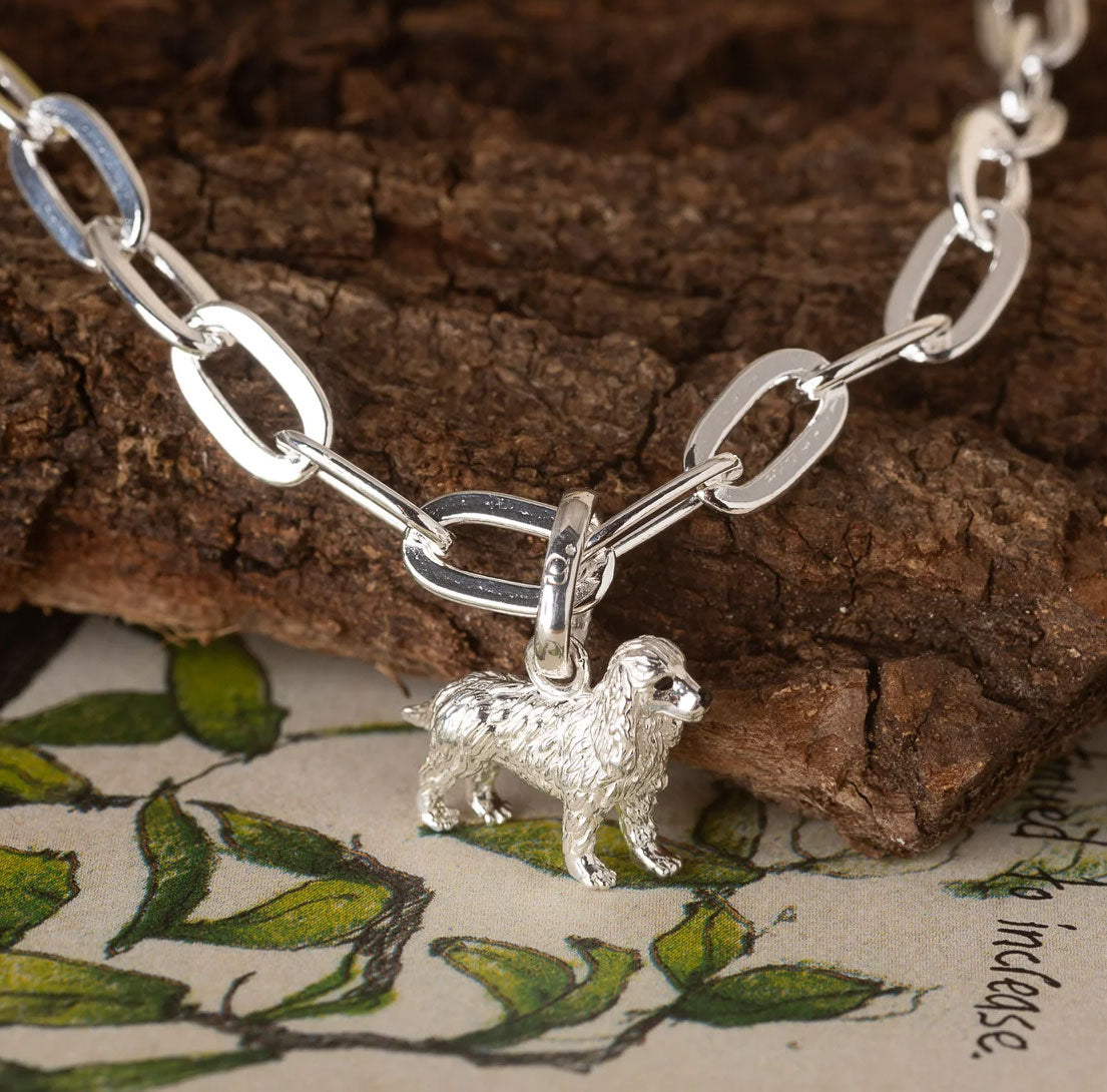 Silver chain bracelet with a dog charm on a wooden surface