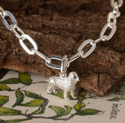 Silver chain bracelet with a dog charm on a wooden surface