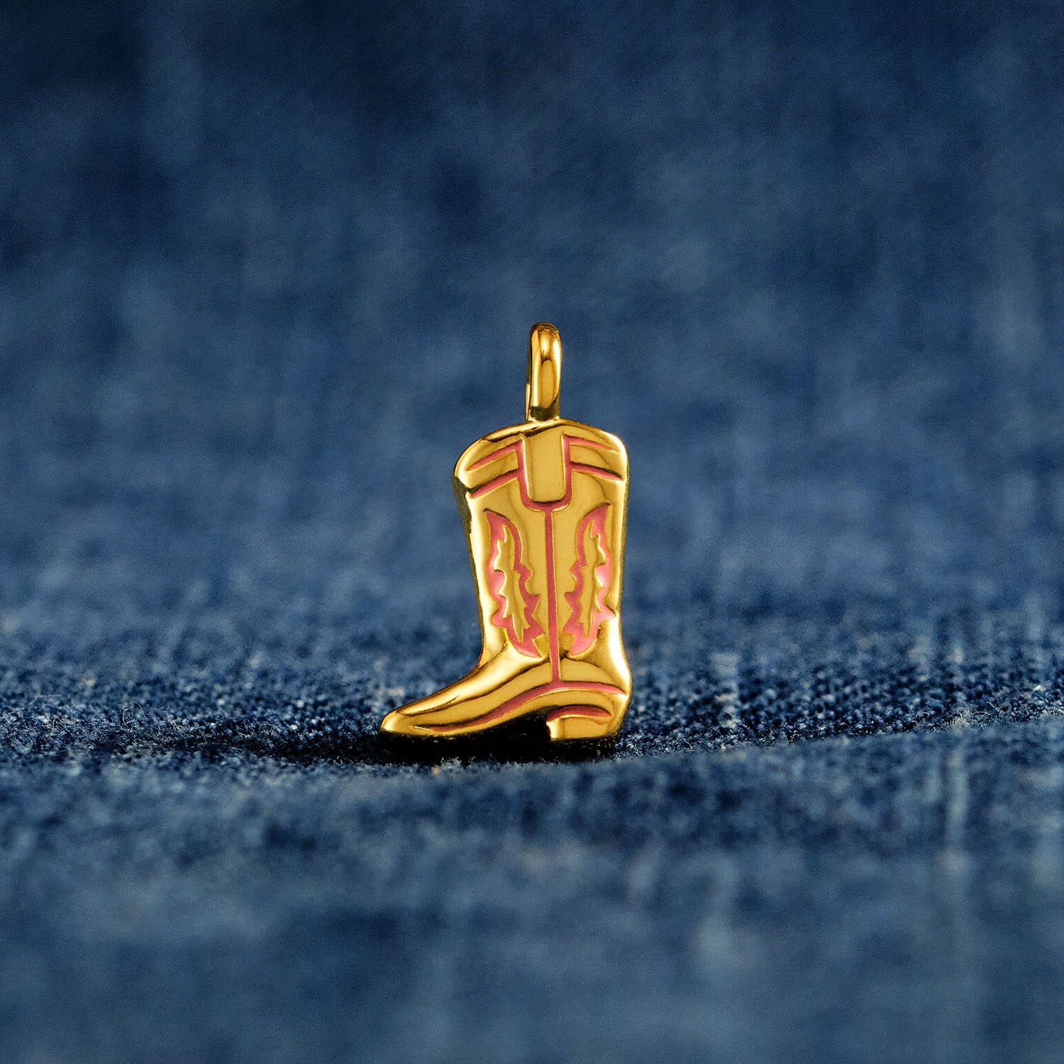 Gold cowboy boot charm on a blue denim background