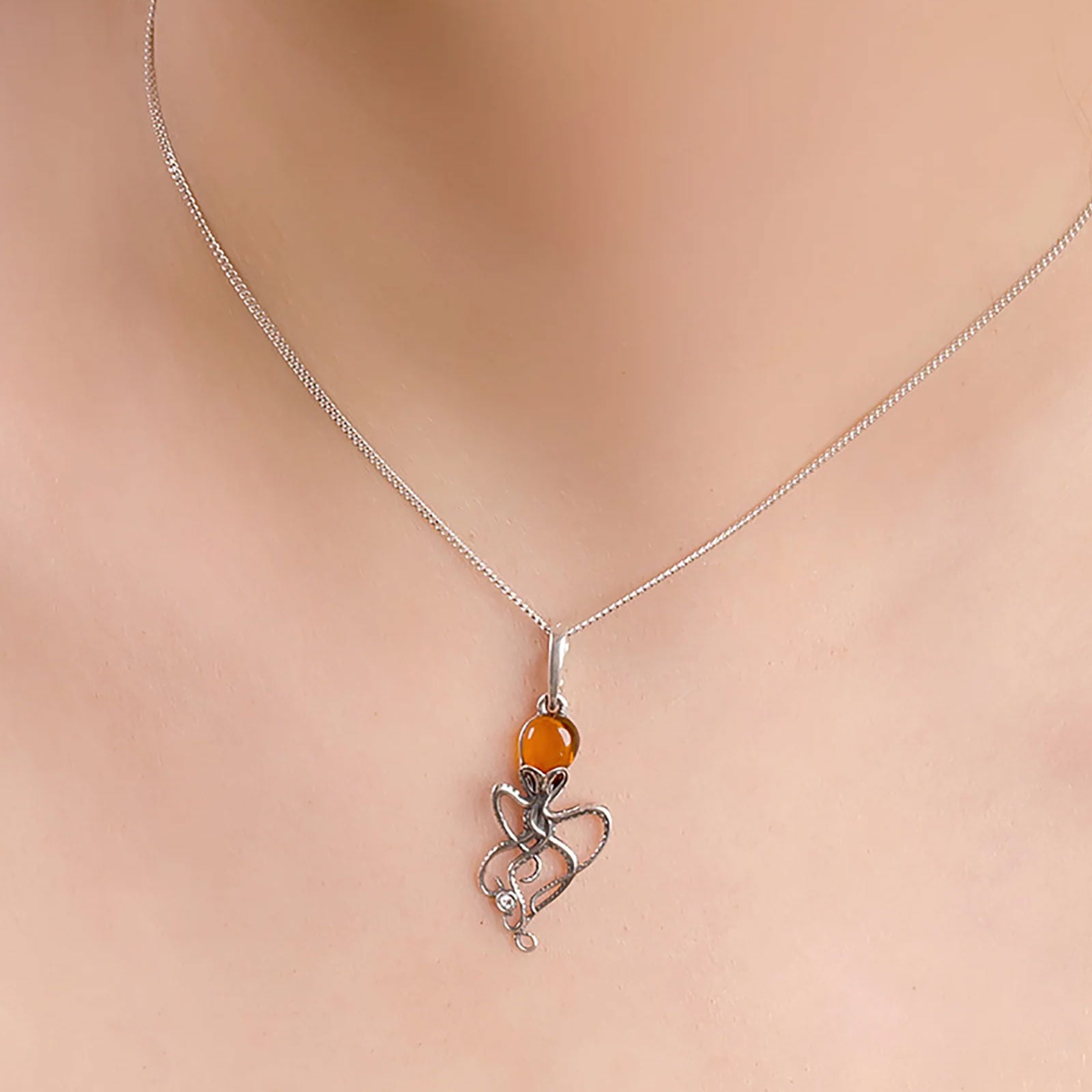 Necklace with an octopu pendant and orange bead on a soft pink lady