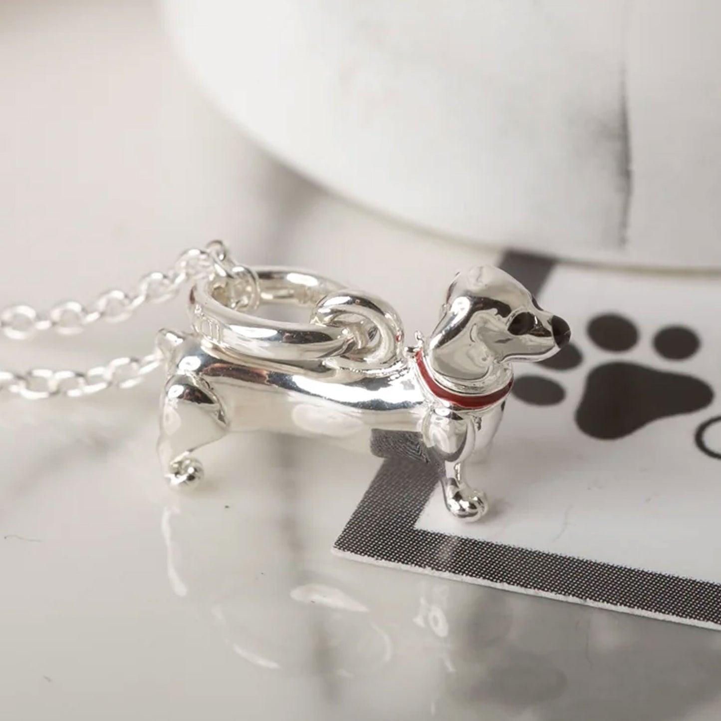 Silver dog-shaped pendant on a chain with a white background