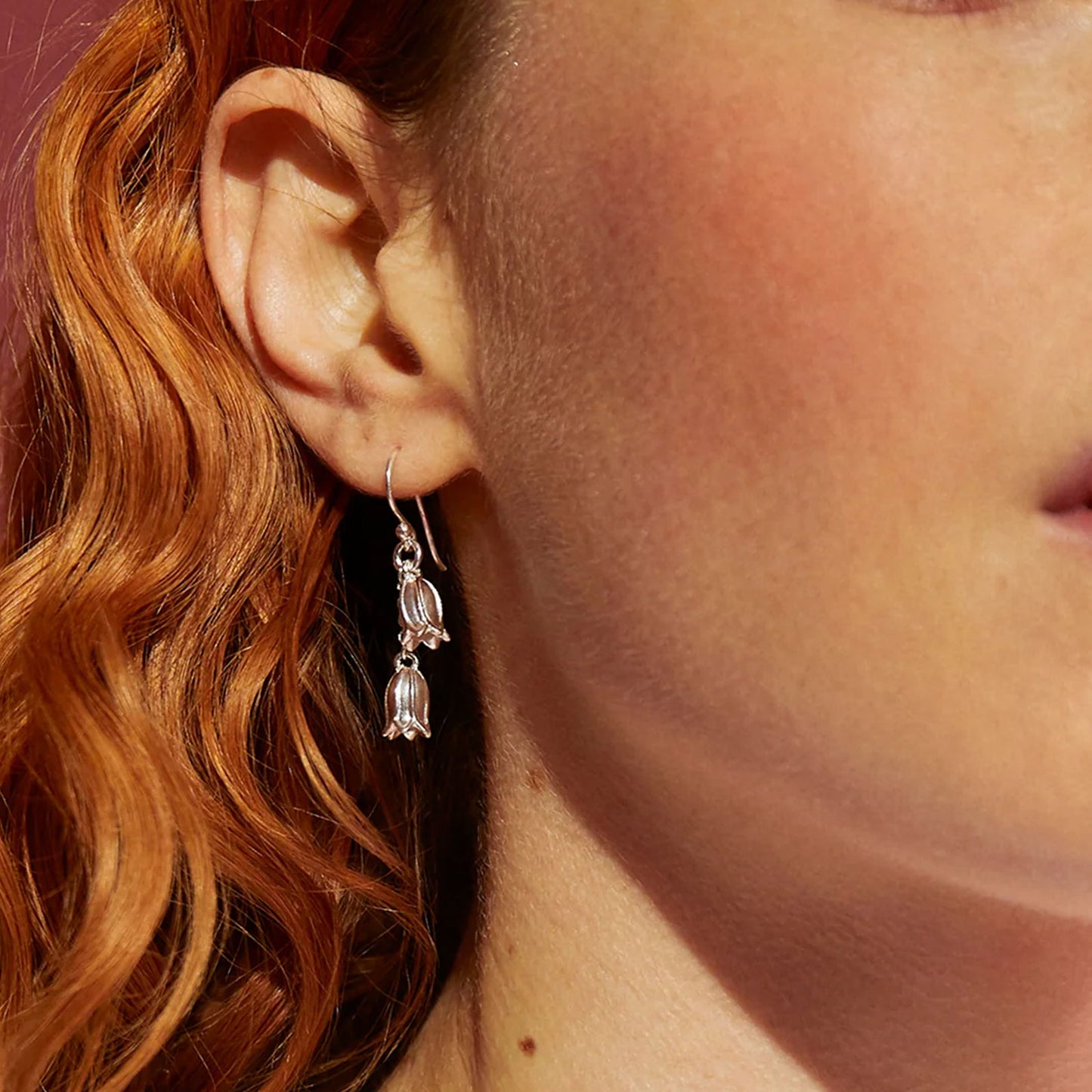 Close-up of a person wearing a silver earring with dangling elements.