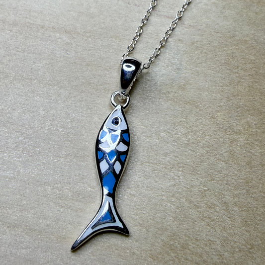Fish-shaped pendant on a chain against a beige background