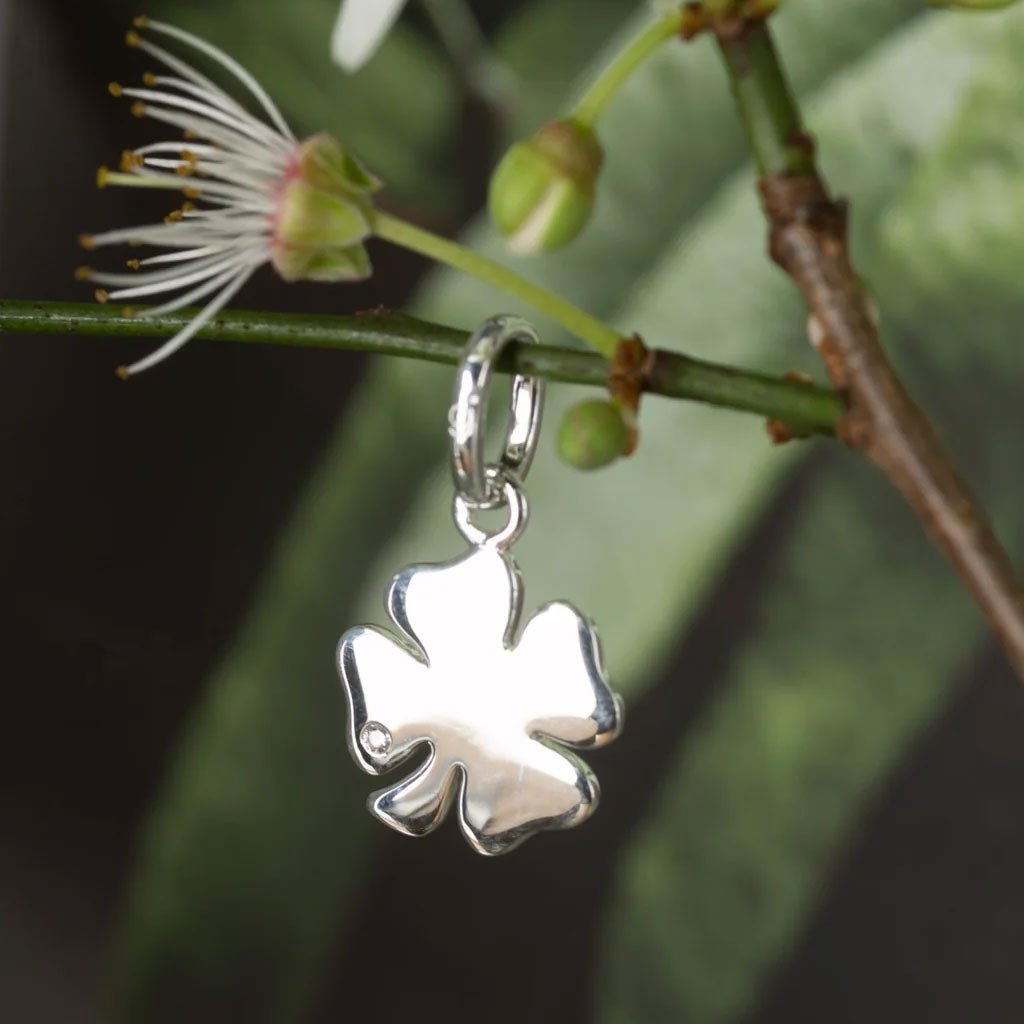 Four Leaf Clover Recycled Sterling Silver Charm on twig on coloured background