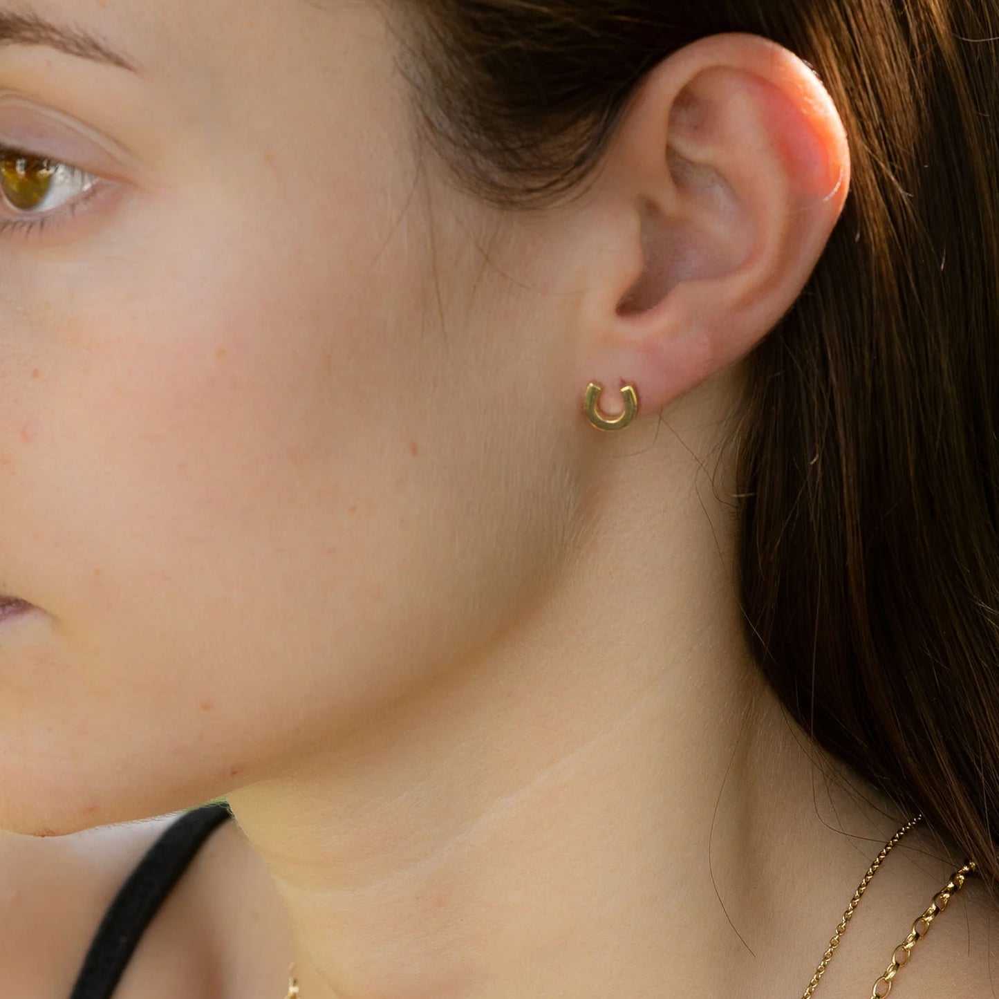 Close-up of a person wearing a gold earring.