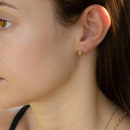 Close-up of a person wearing a gold earring.