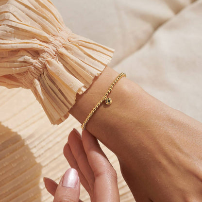 Gold bracelet on a wrist with a blurred background