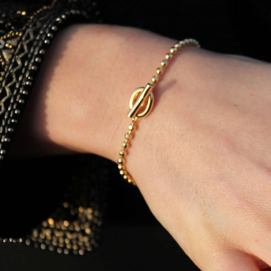 Gold bracelet on a wrist with a dark background
