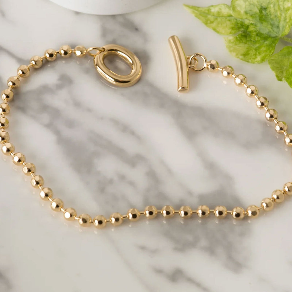 Gold TBar charm bracelet on marble background