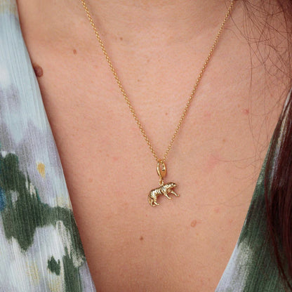 Gold necklace with a bear pendant on a person's neck