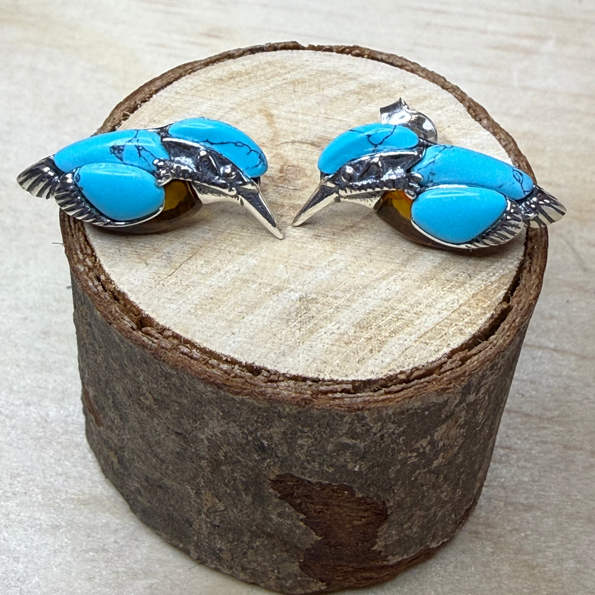 Pair of turquoise earrings on a wooden display block