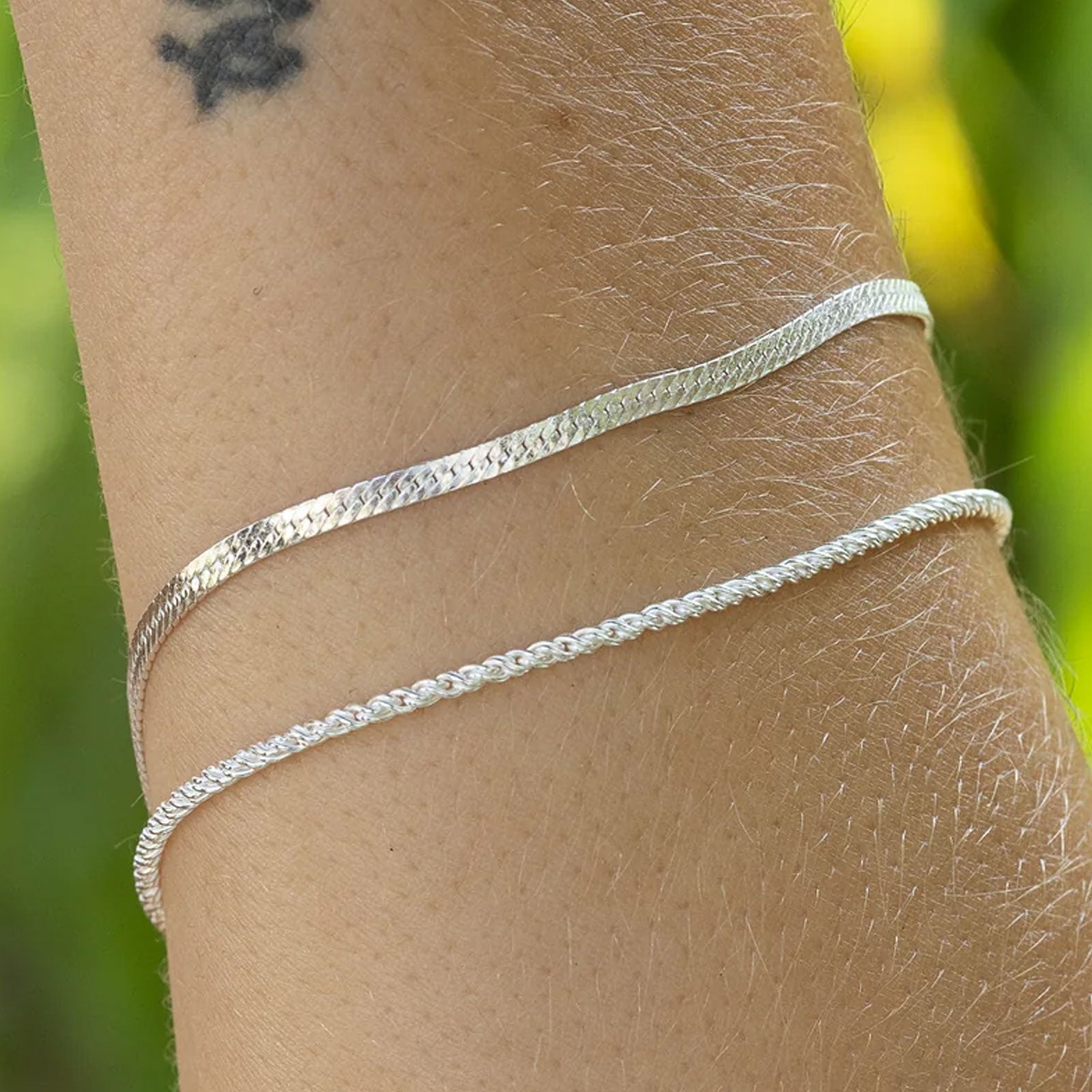 Silver bracelet on a wrist with a blurred green background