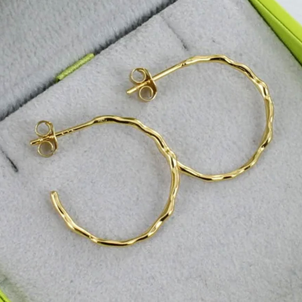 Gold hoop earrings on a textured surface