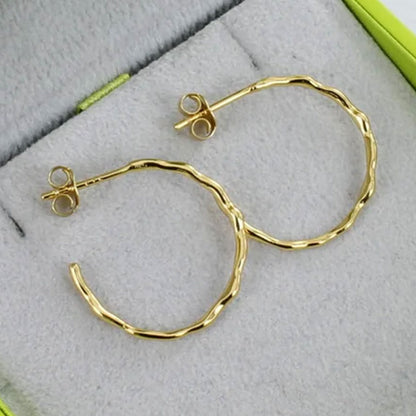 Gold hoop earrings on a textured surface