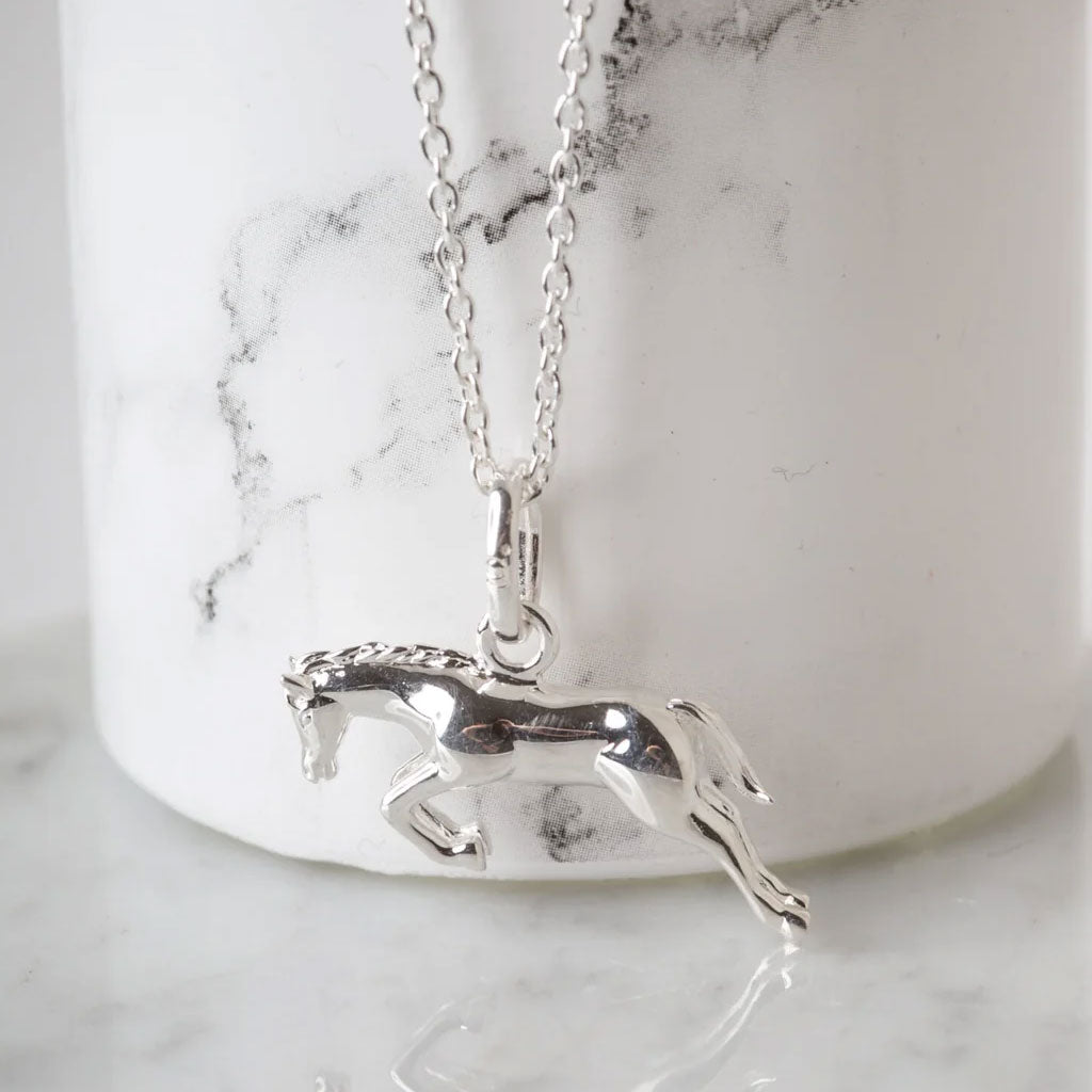 Silver horse pendant necklace on a marble surface