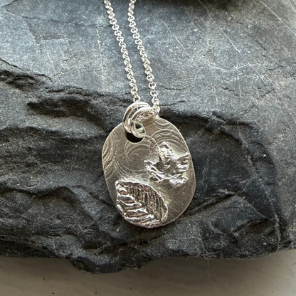 Silver necklace with a pendant on a stone surface