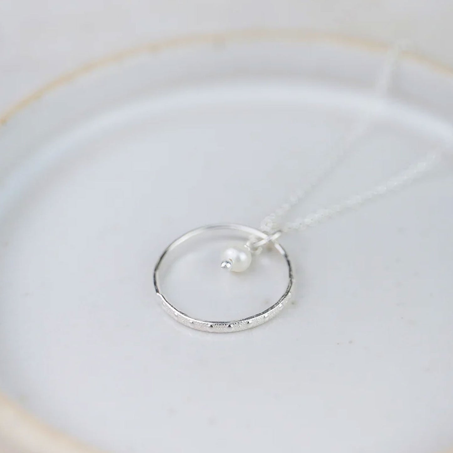 Silver ring with a pearl on a white dish