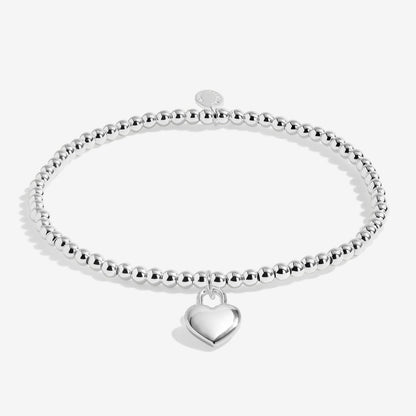 Silver beaded bracelet with a heart charm on a white background