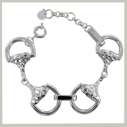 A silver-tone bracelet featuring horsebit-inspired rings with textured details and clear rhinestone accents, shown on a plain white background.