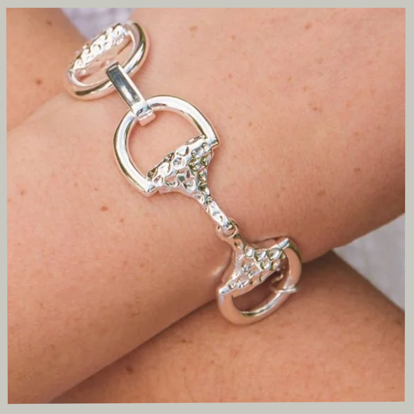 A sterling silver horsebit bracelet with textured details, shown worn on a person's wrist.