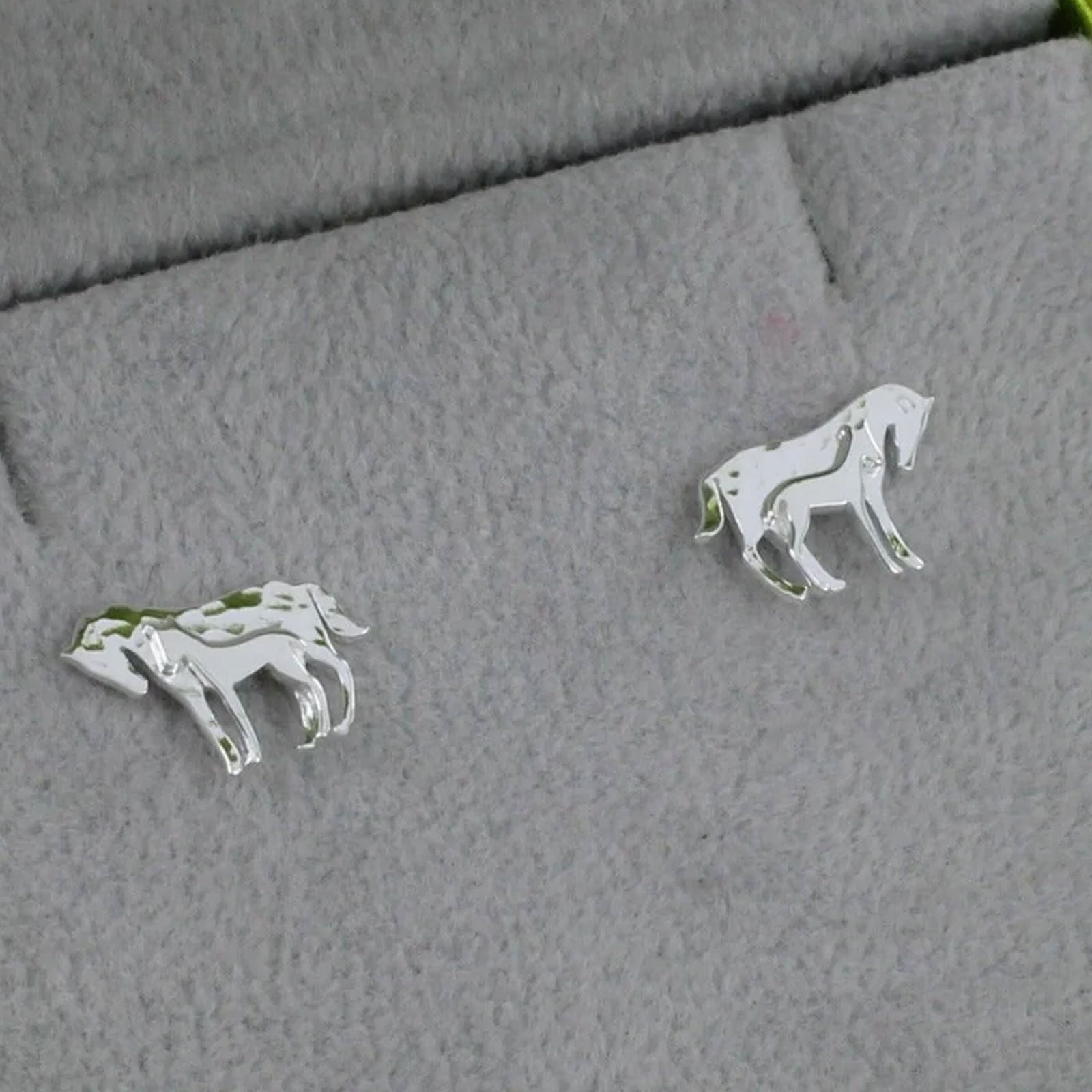 mare and foal earrings on grey cloth background